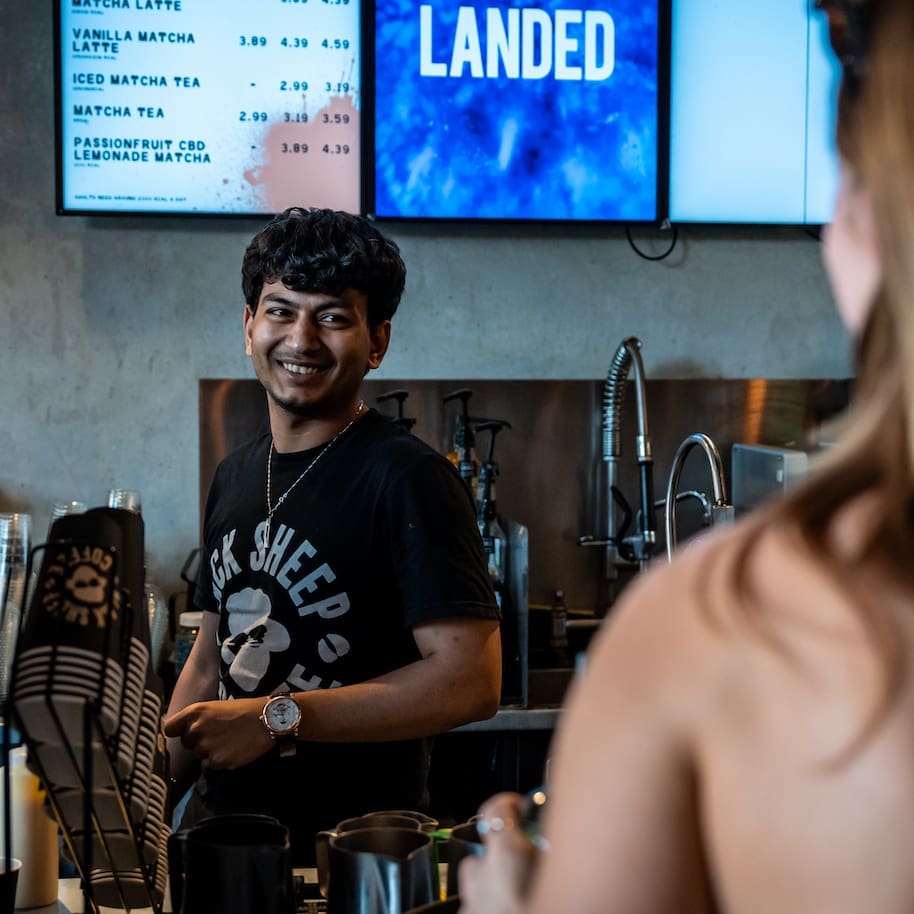 Barista at Black Sheep Coffee serving a customer